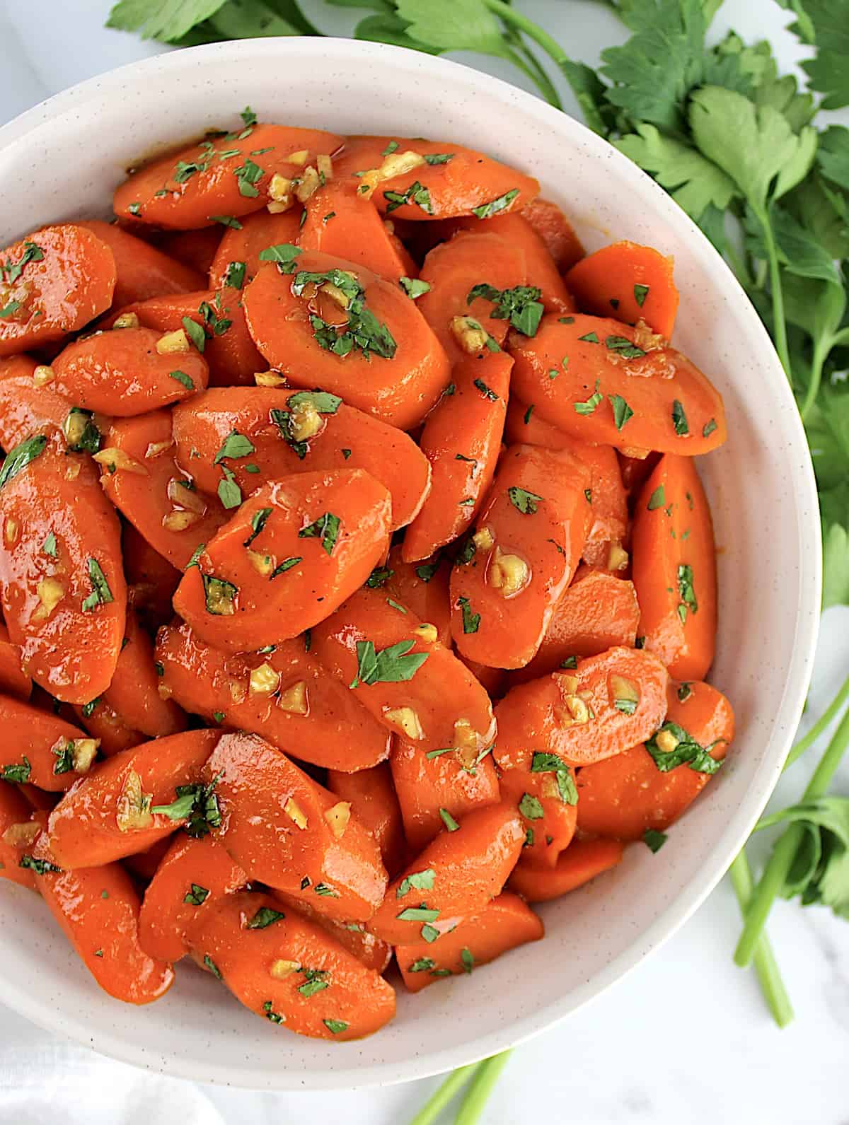 Glazed Carrots with chopped parsley on top in white bowl