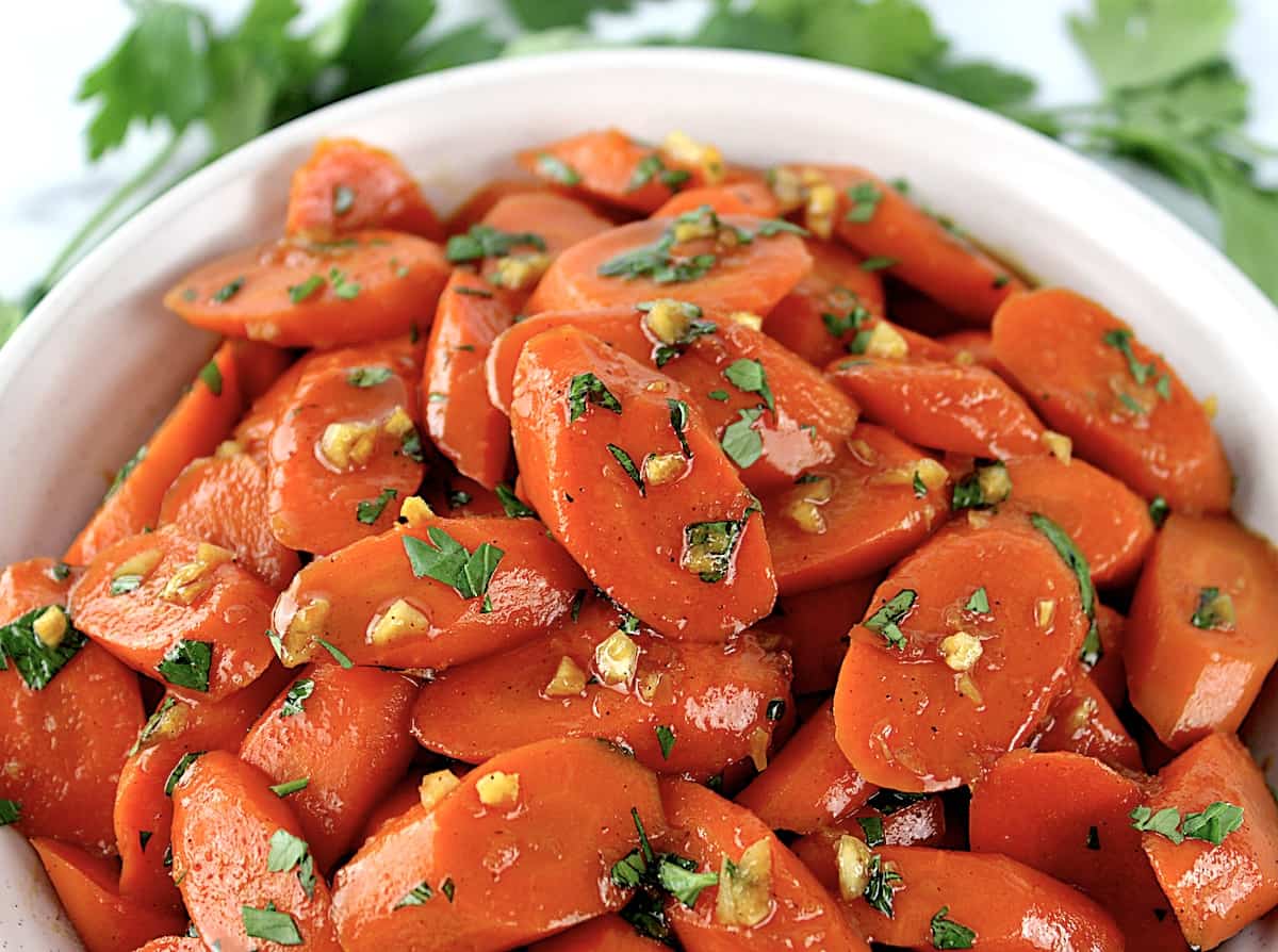 Glazed Carrots with chopped parsley on top in white bowl