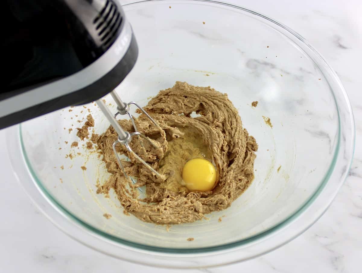 creamed butter and coconut sugar with raw egg being mixed in glass bowl