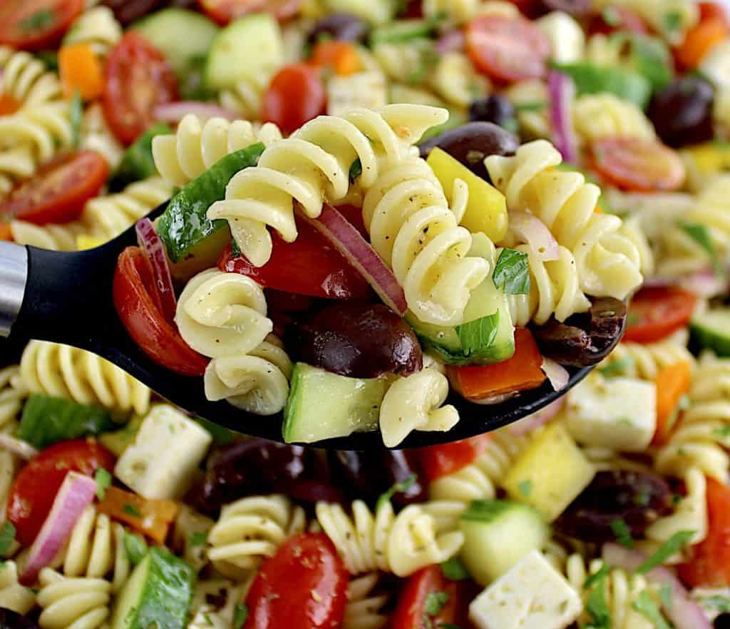 black serving spoon with Greek Pasta Salad