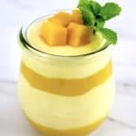 layered Mango Mousse in glass jar with mango chunks and mint sprig on top