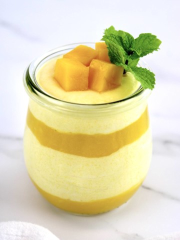 layered Mango Mousse in glass jar with mango chunks and mint sprig on top