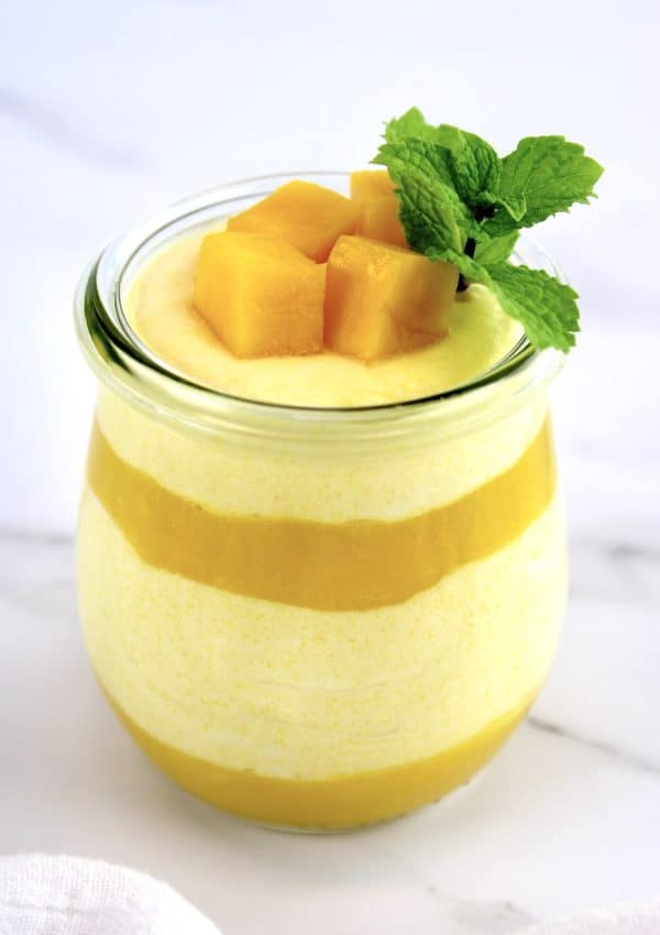 layered Mango Mousse in glass jar with mango chunks and mint sprig on top