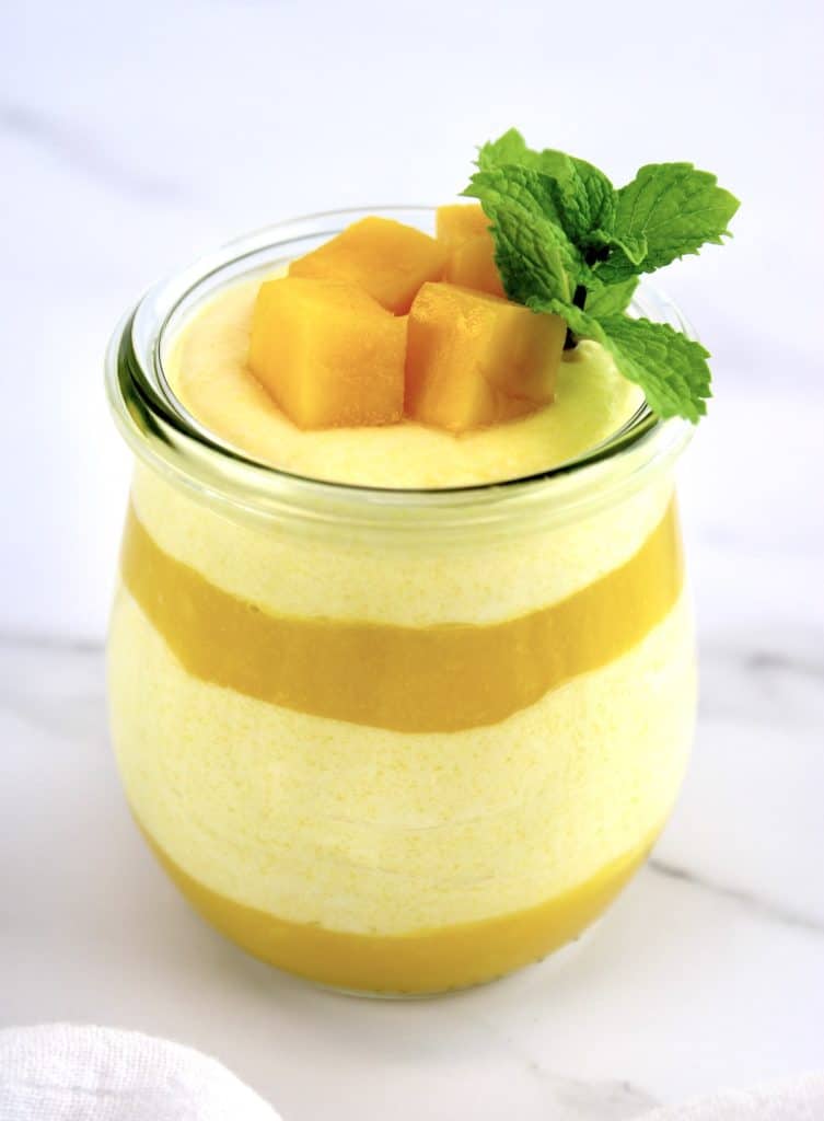 layered Mango Mousse in glass jar with mango chunks and mint sprig on top