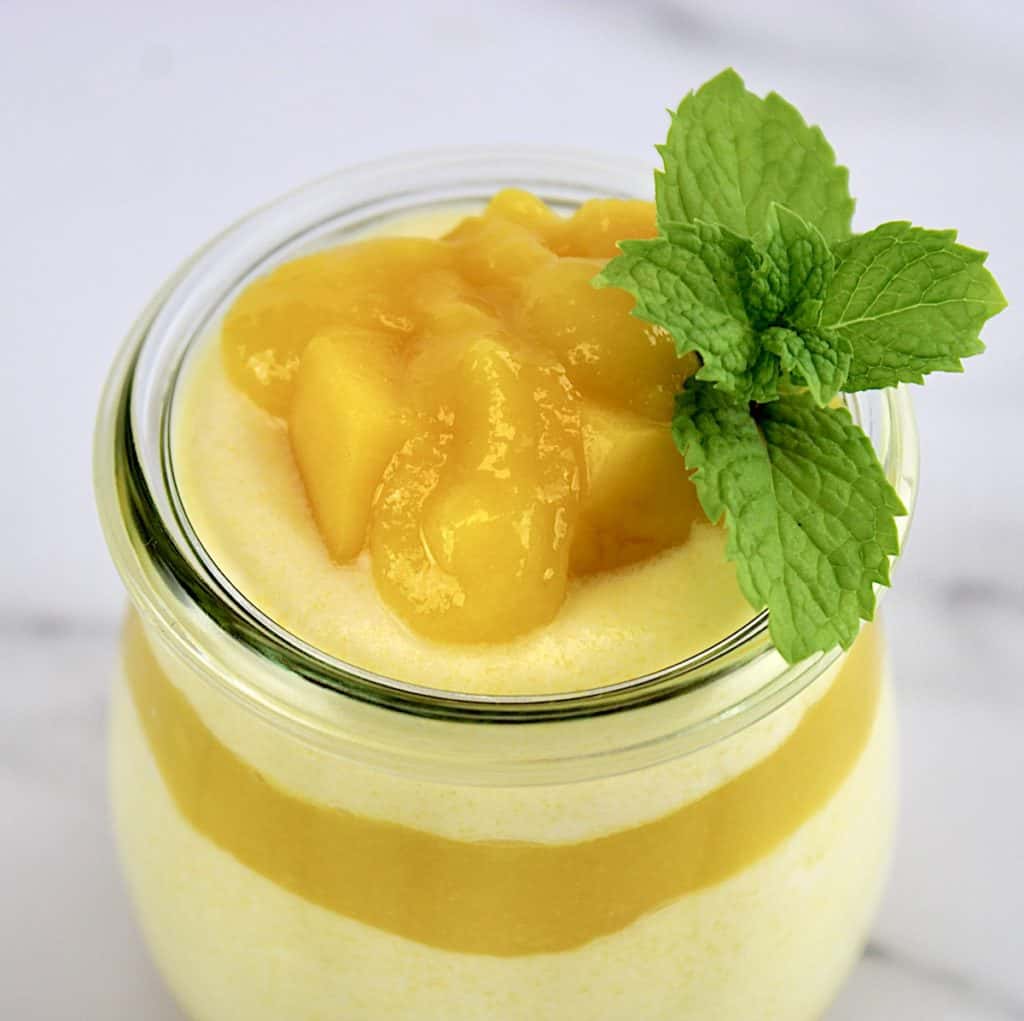 closeup of Mango Mousse in glass jar with mango puree and mint on top