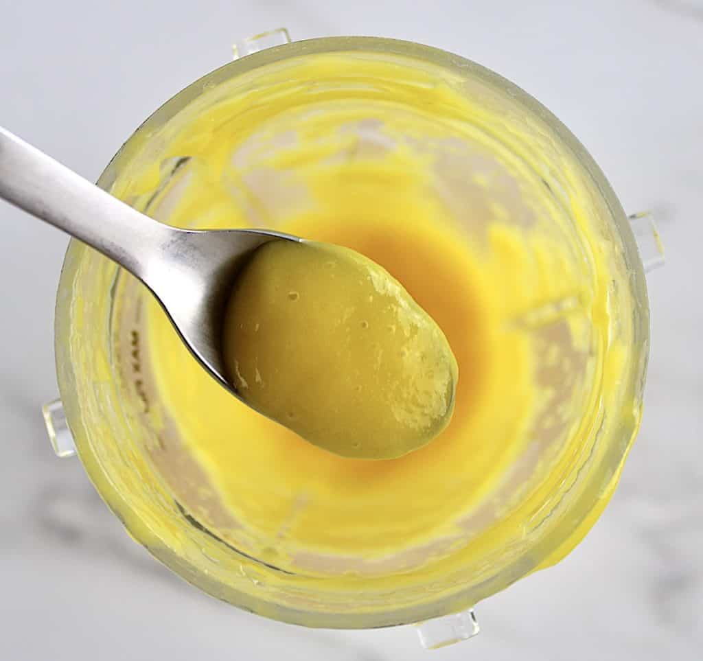 pureed mango in spoon held up over bullet blender