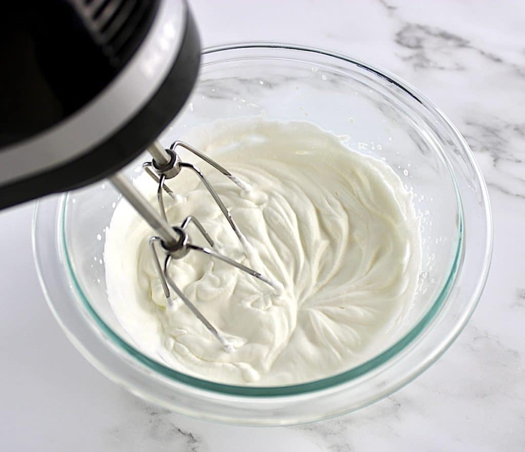whip cream being whipped in glass bowl with hand mixer