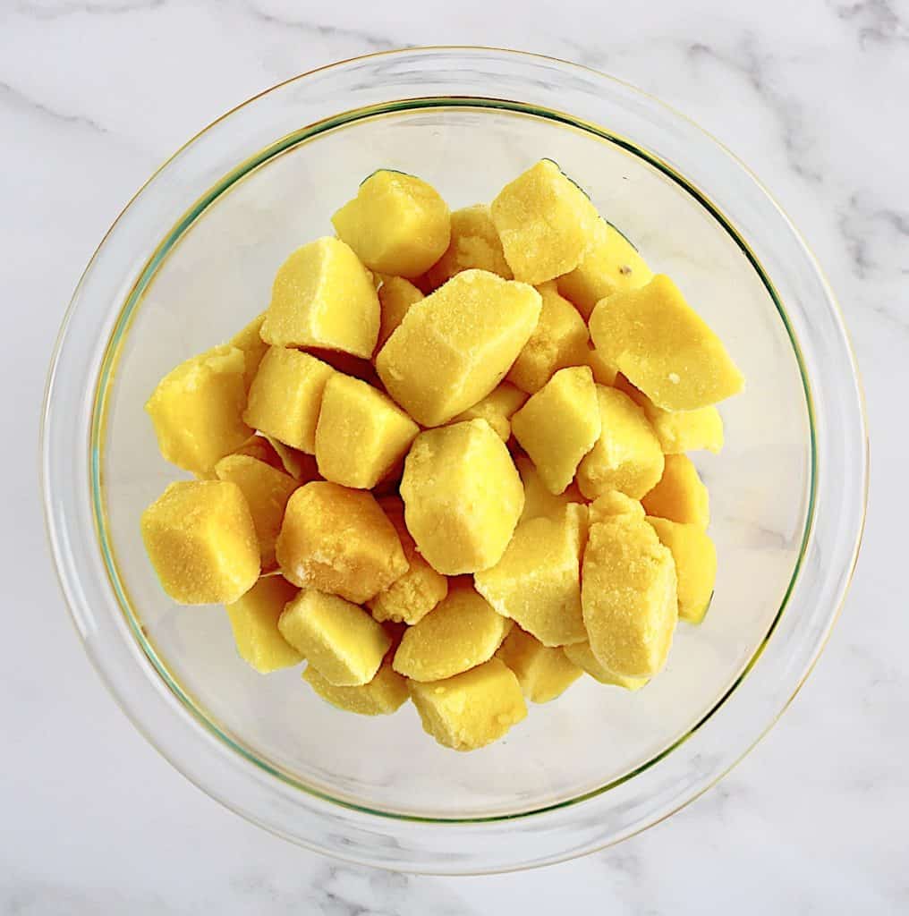 frozen mango chunks in glass bowl