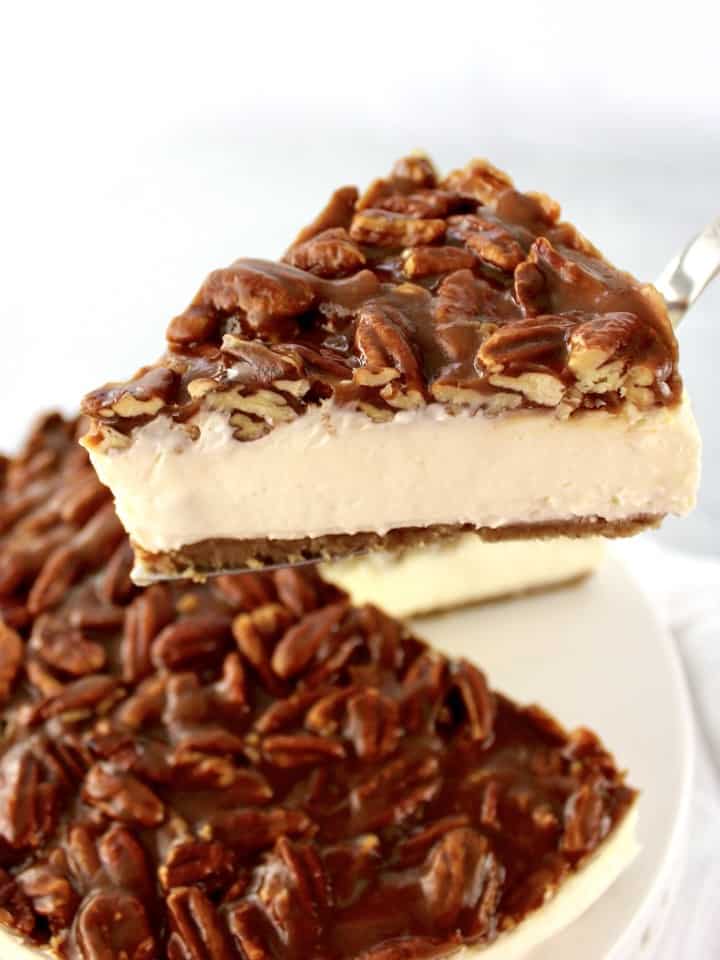 slice of pecan pie cheesecake being held up with cake server