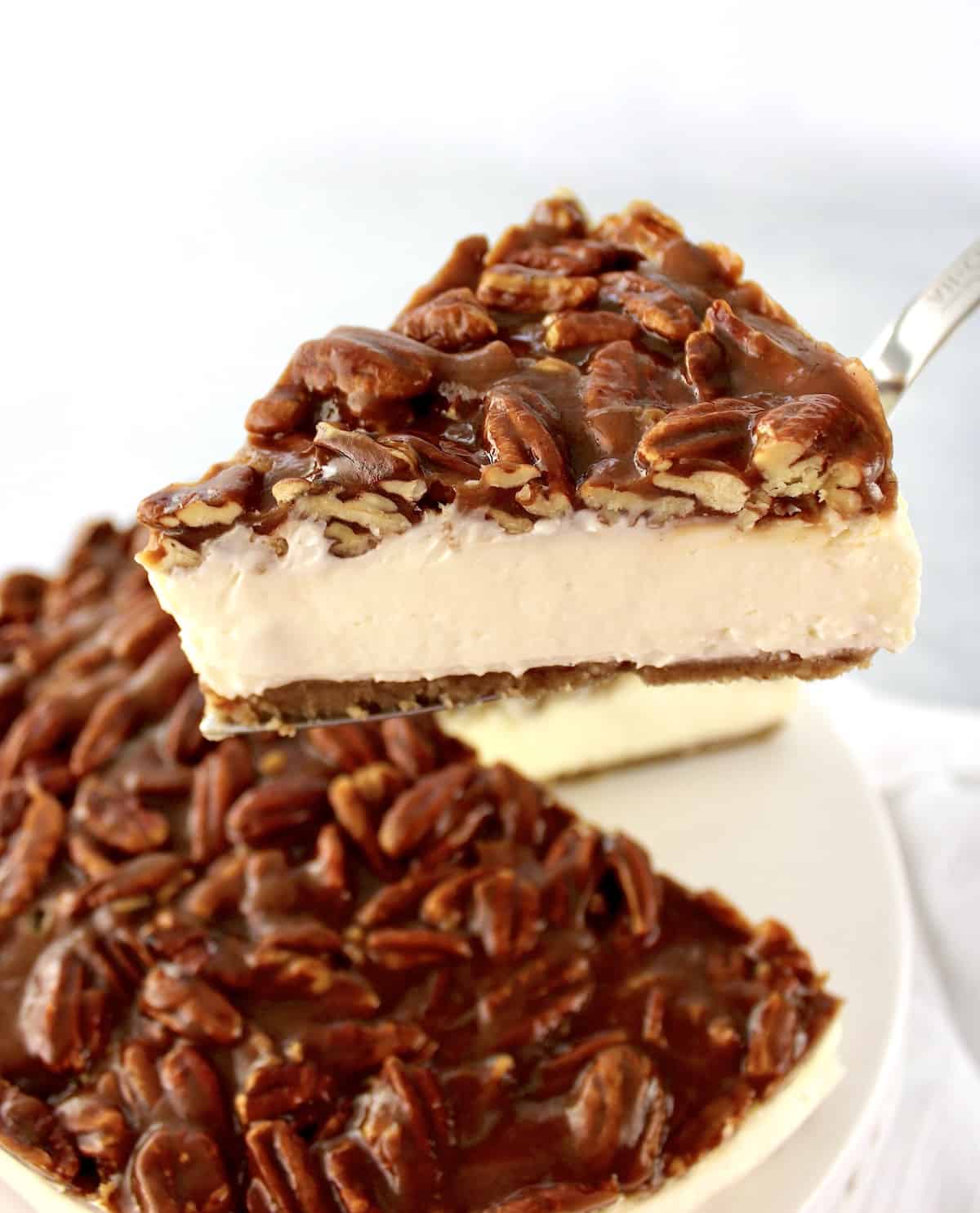 slice of pecan pie cheesecake being held up with cake server