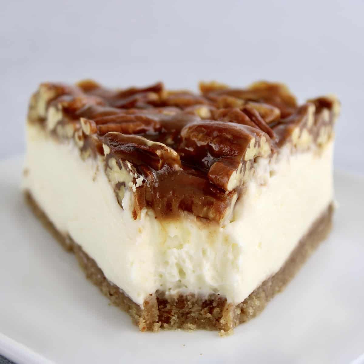 Keto Pecan Pie Cheesecake slice on white plate with bite missing