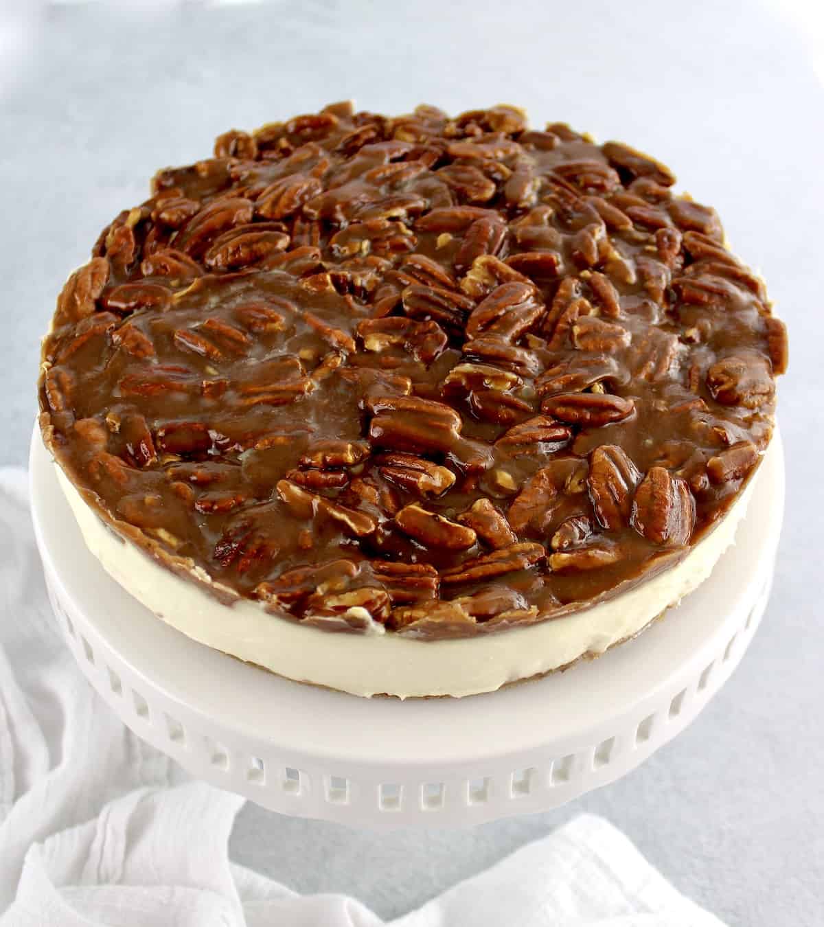Keto Pecan Pie Cheesecake on white cake stand