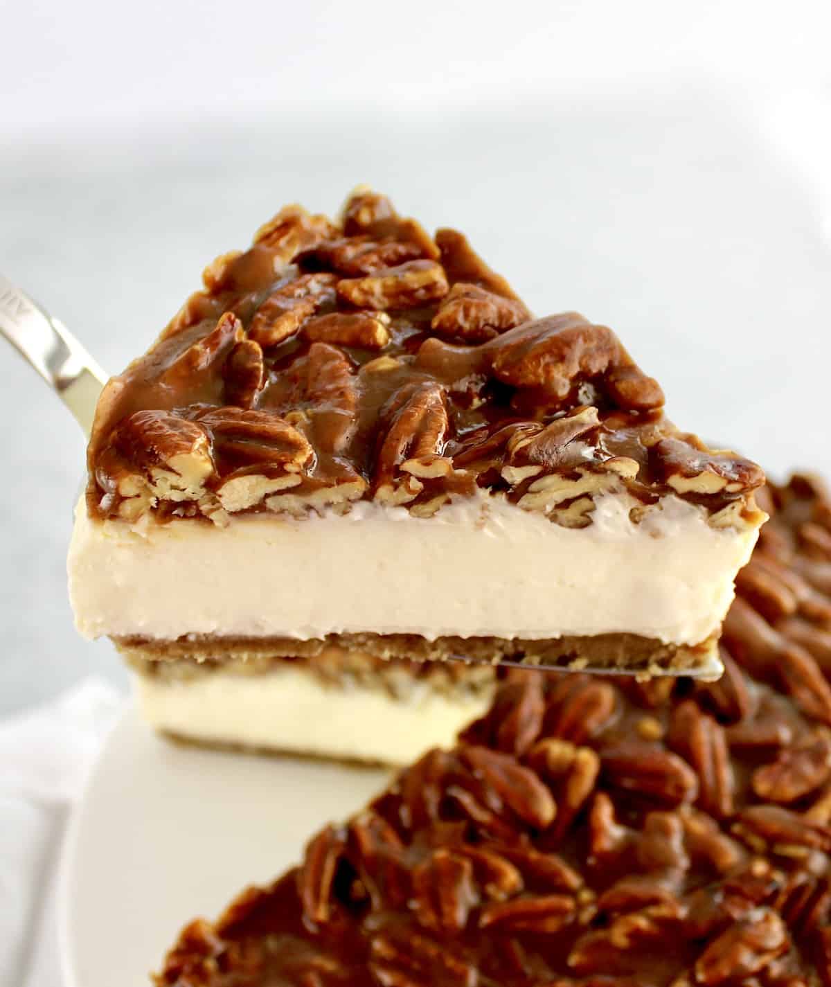 slice of pecan pie cheesecake being held up with cake server