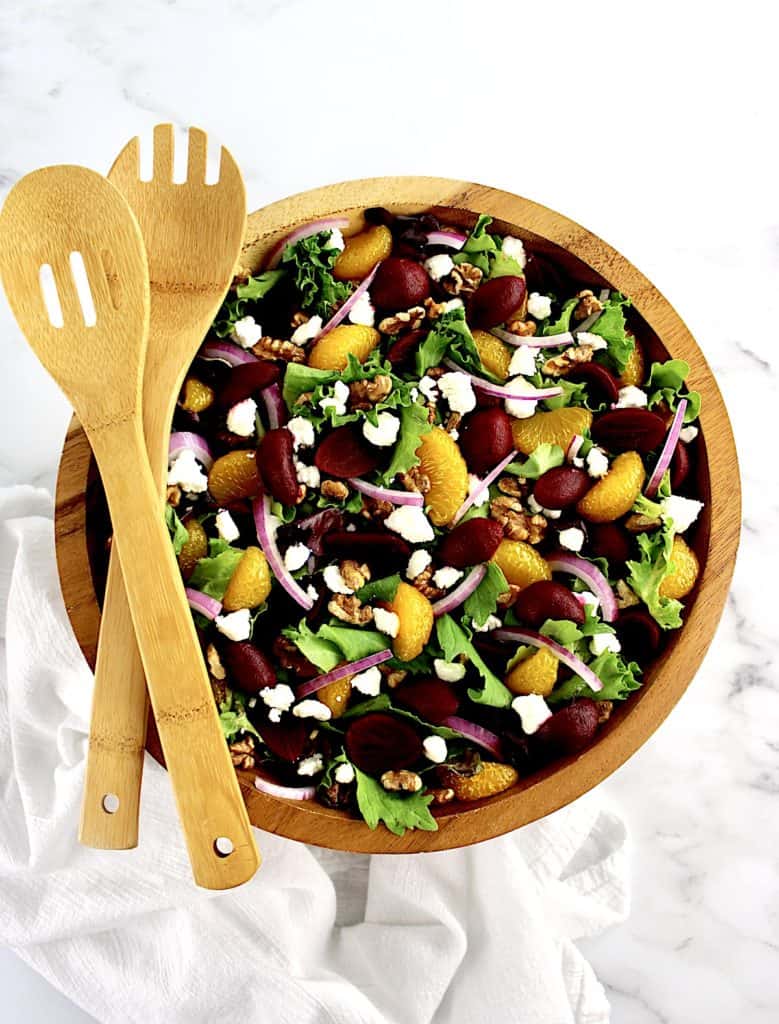 overhead view of Pickled Beet Salad in wooden bowl with wooden serving spoons on side