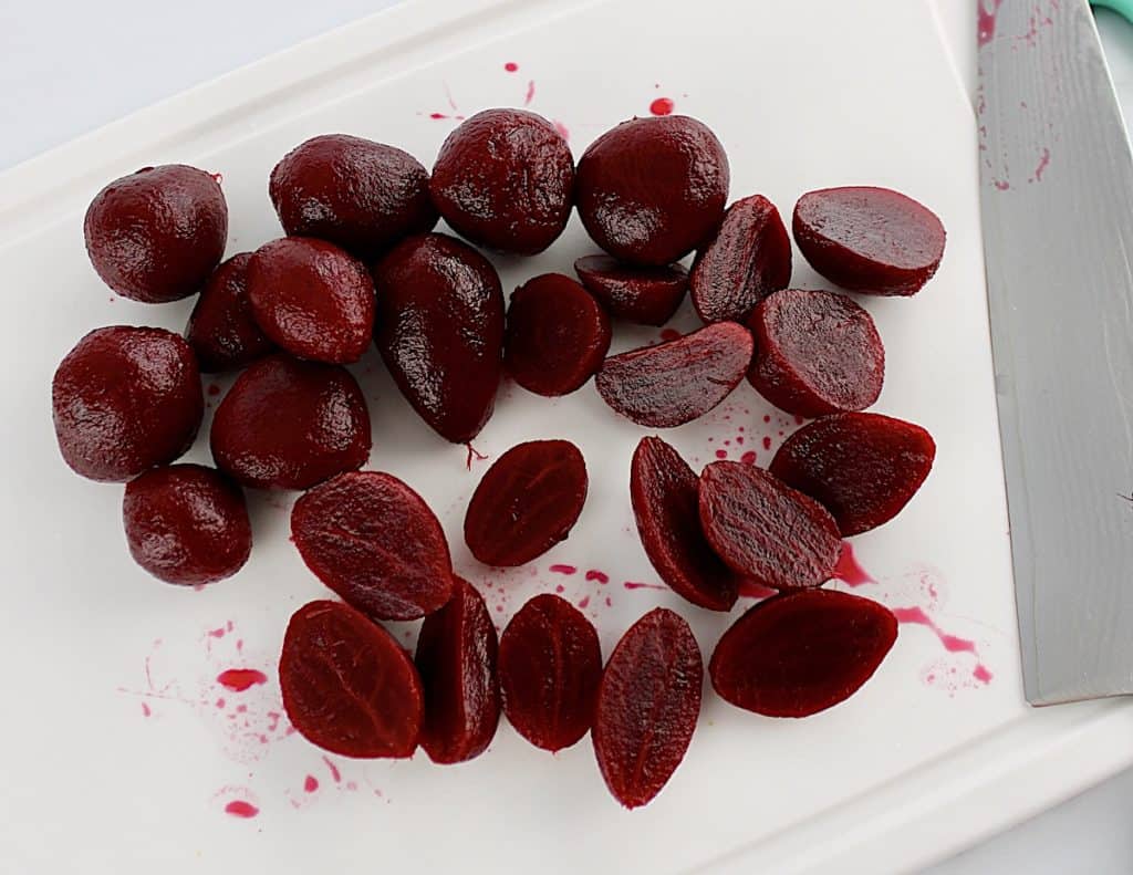 pickled baby beets on white cutting board sliced