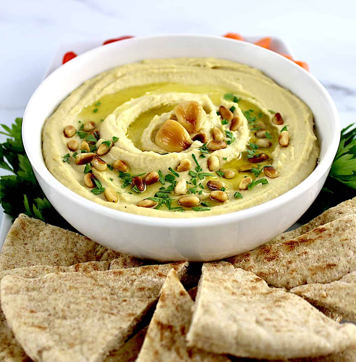 bowl of Roasted Garlic Hummus with pita wedges on side