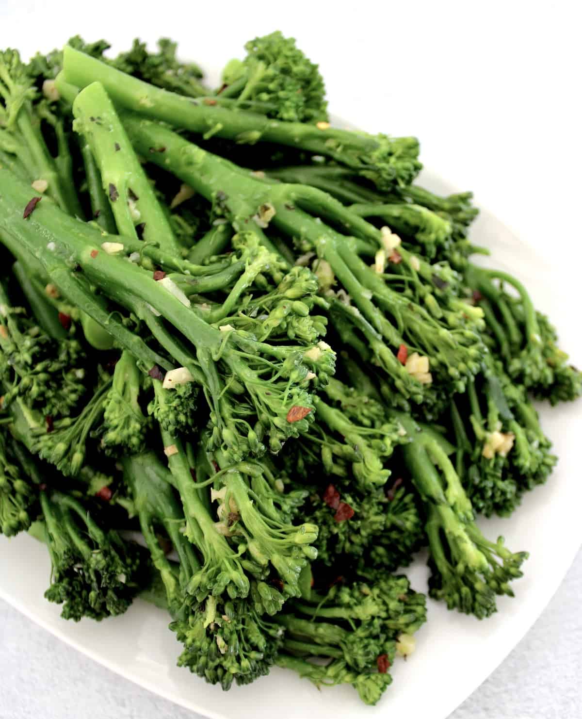 Sautéed Broccolini with Garlic on white plate with red pepper flakes