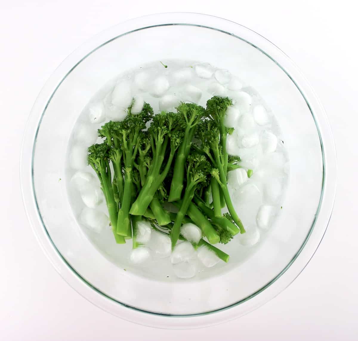broccolini in water with ice in glass bowl