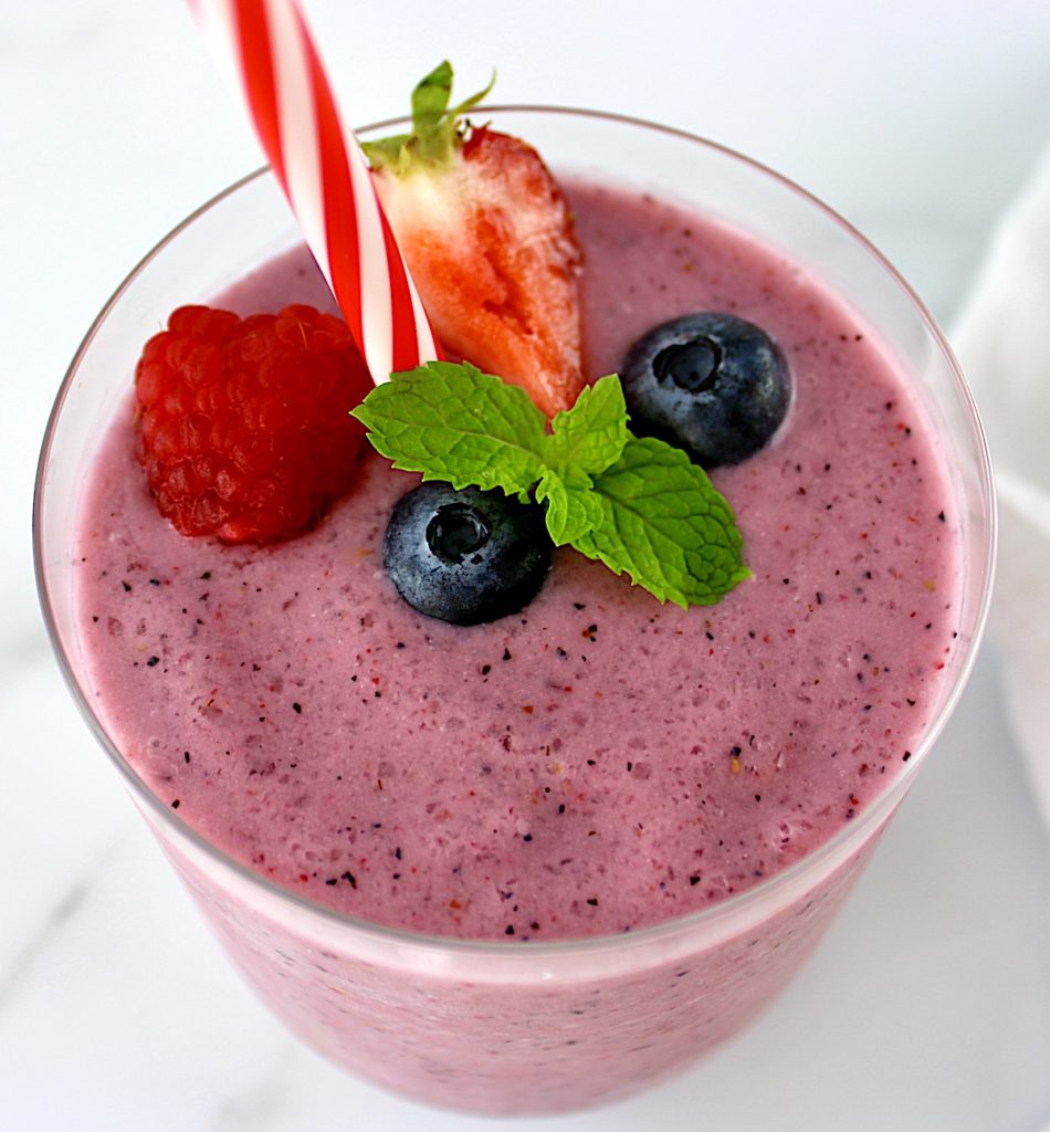 Triple Berry Smoothie in glass with berries and mint sprig on top