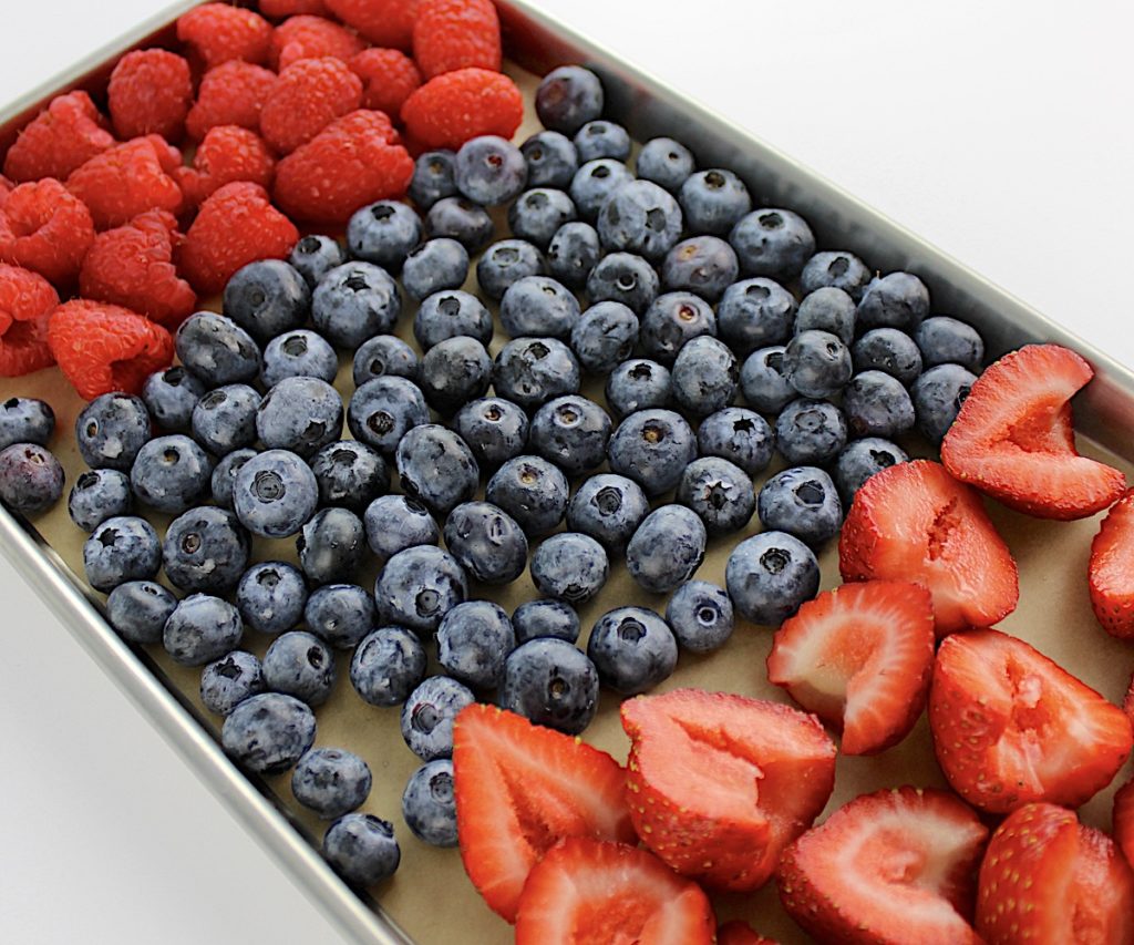 raspberries blueberries and strawberries on baking sheet with parchment paper