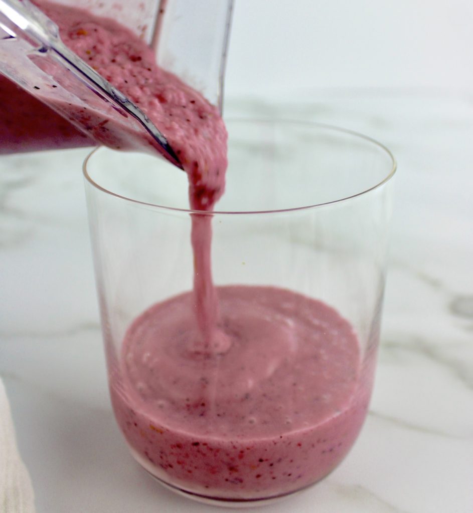 Triple Berry Smoothie being poured from blender into glass bowl