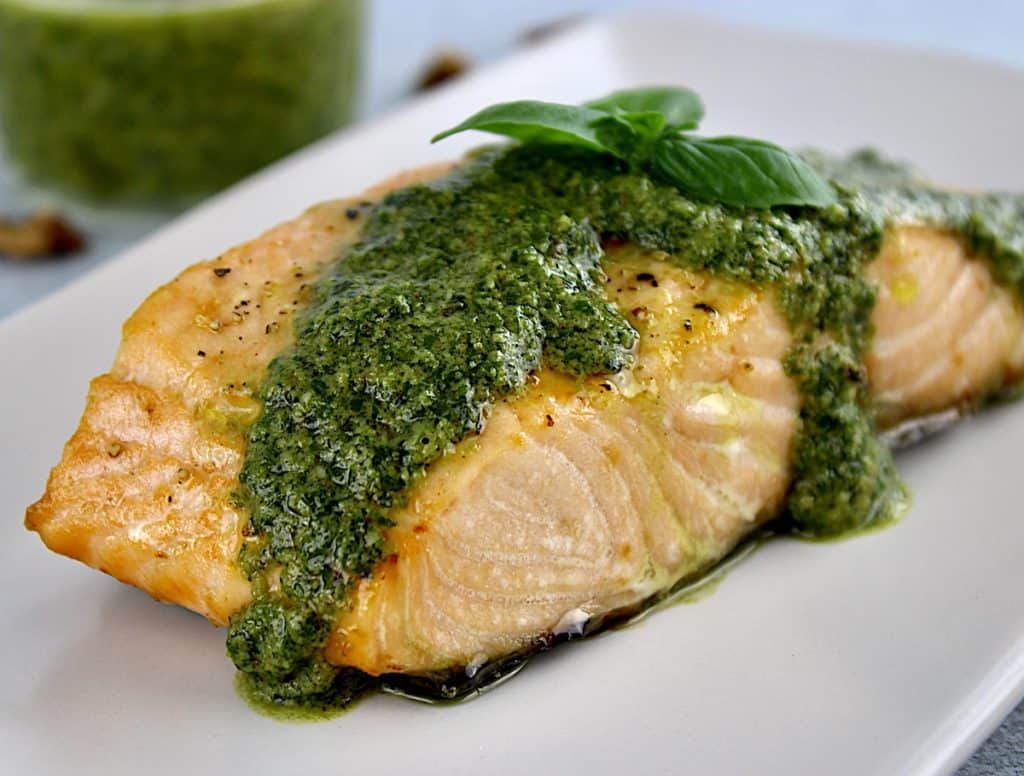 walnut pesto dripped on top of salmon on white plate