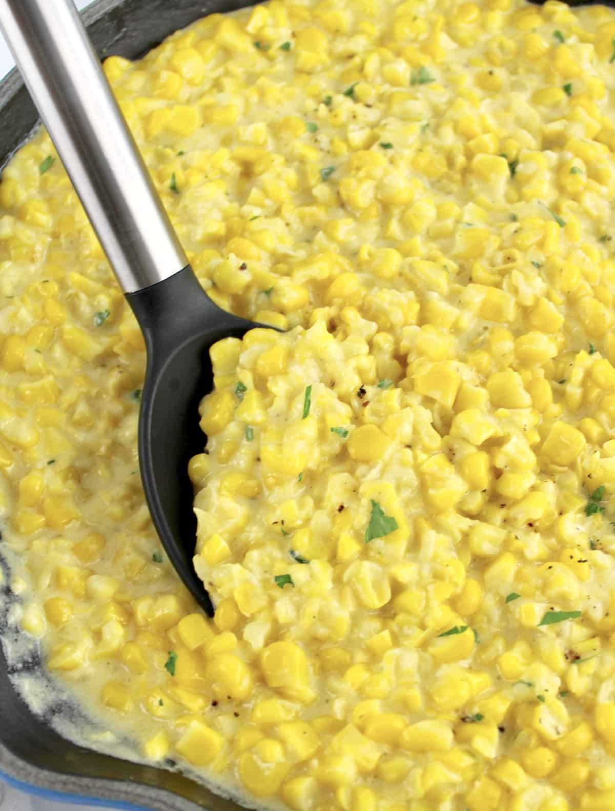 closeup of Creamed Corn in skillet with serving spoon
