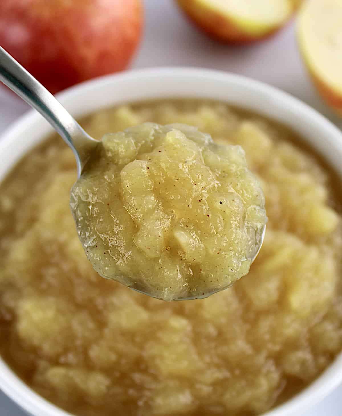 spoonful of Homemade Applesauce held up over white bowl