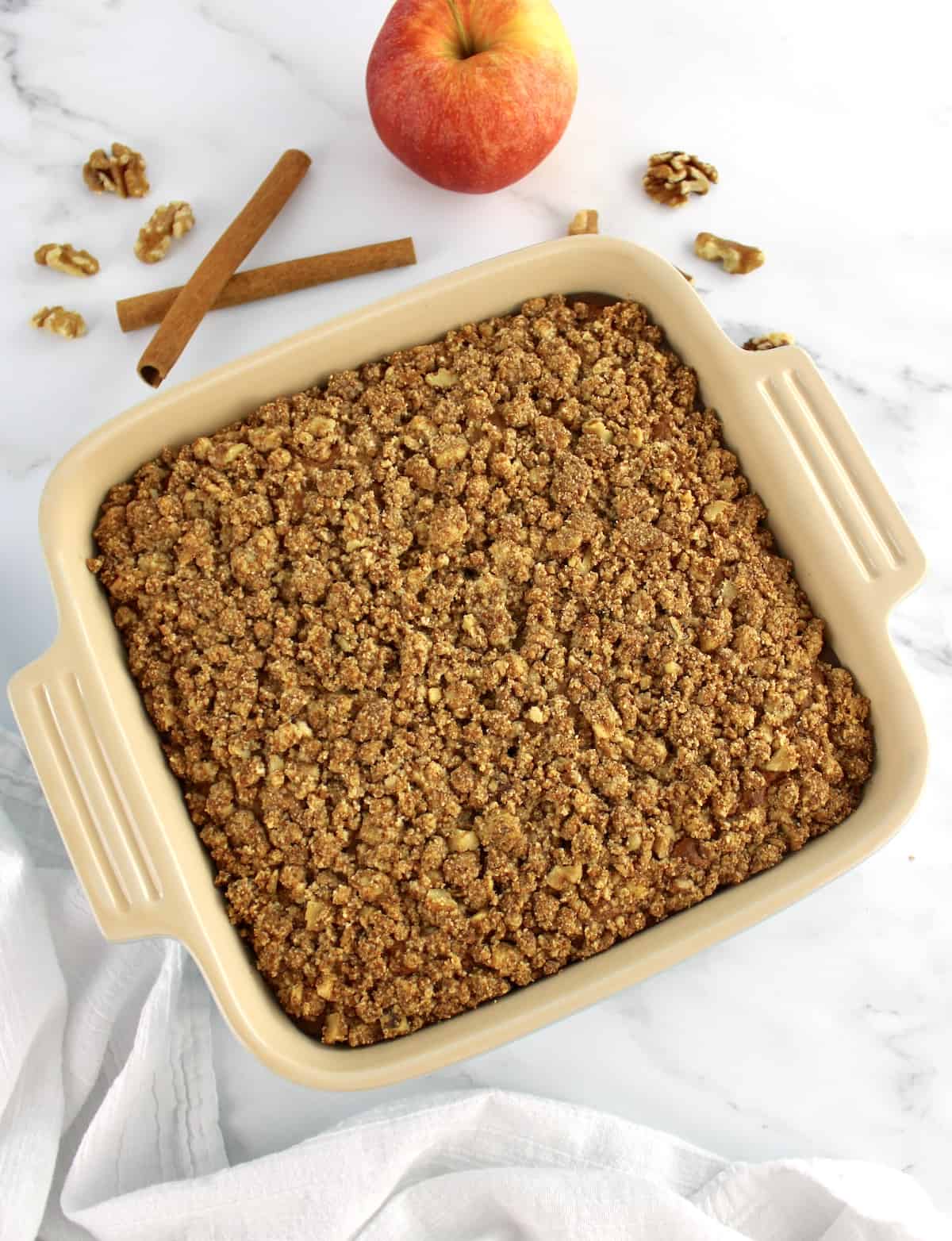 Gluten-Free Apple Cake in baking dish with apple and cinnamon stick in background