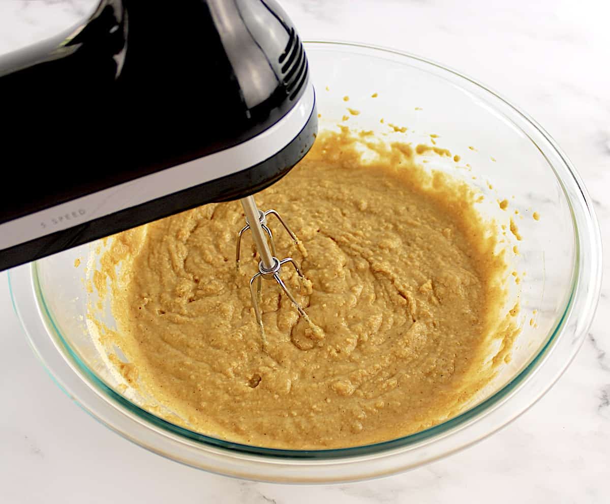Gluten-Free Apple Cake batter being mixed in glass bowl with hand mixer