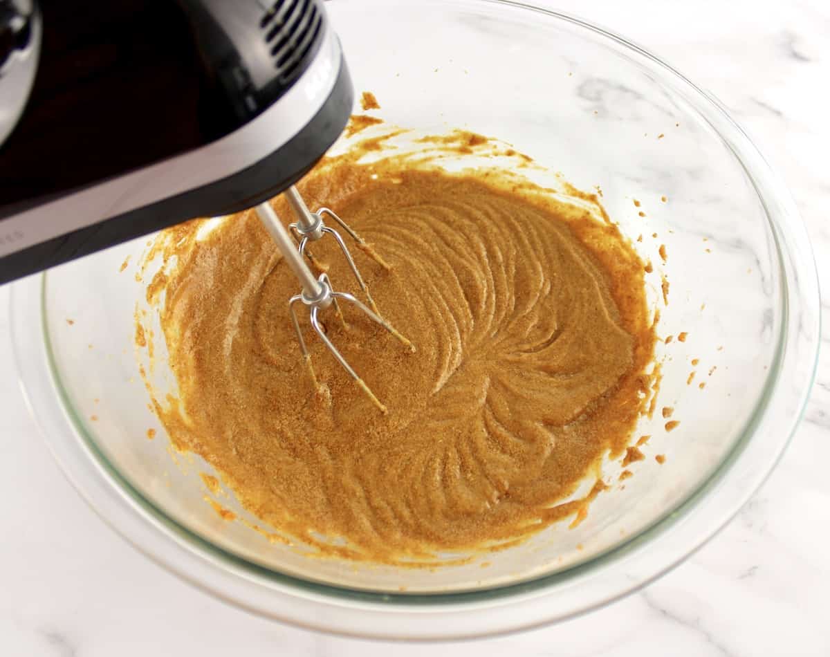 wet ingredients for Gluten Free Pumpkin Cookies being mixed with hand mixer in glass bowl