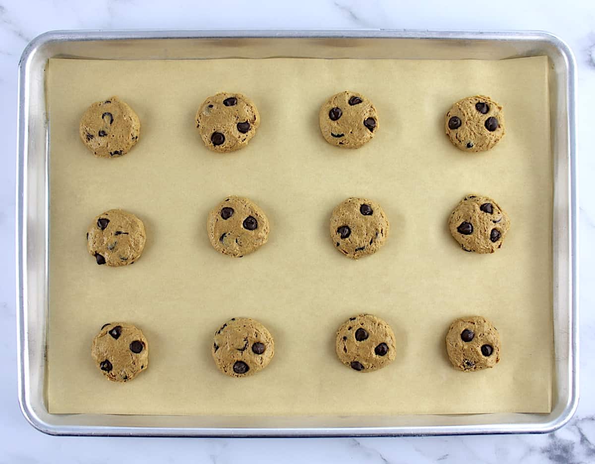 12 cookie dough balls on parchment lined baking sheet