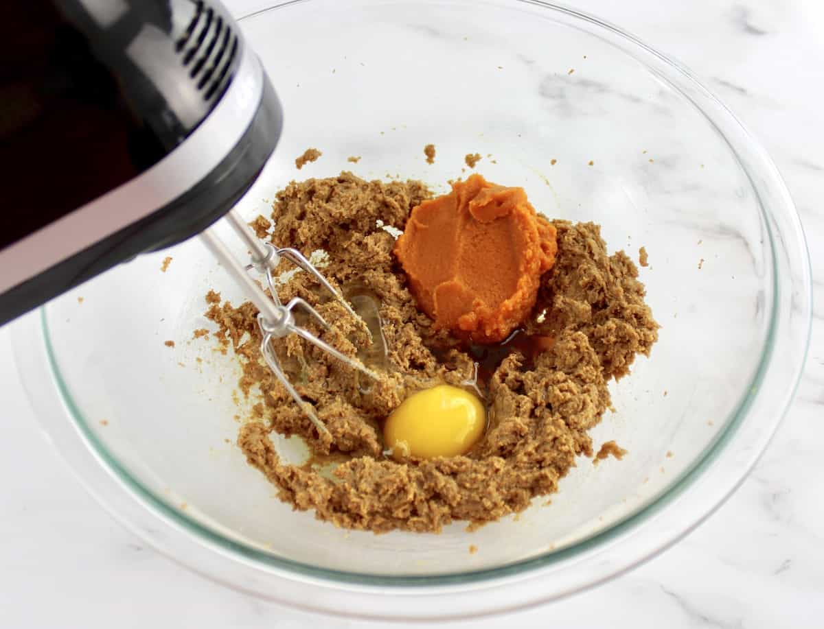 wet ingredients for Gluten Free Pumpkin Cookies in glass bowl with hand mixer
