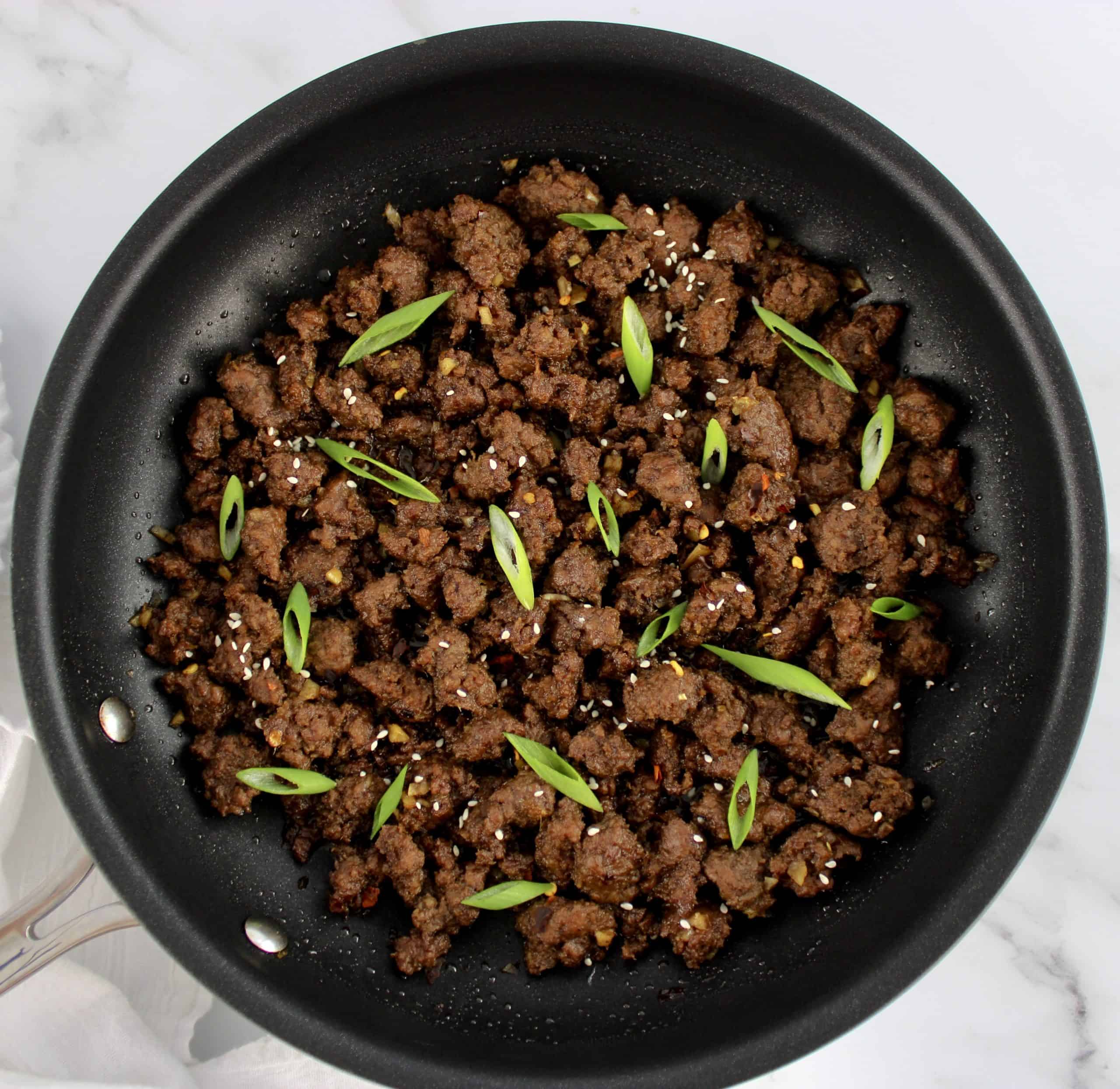 Korean Beef in skillet with sliced scallions