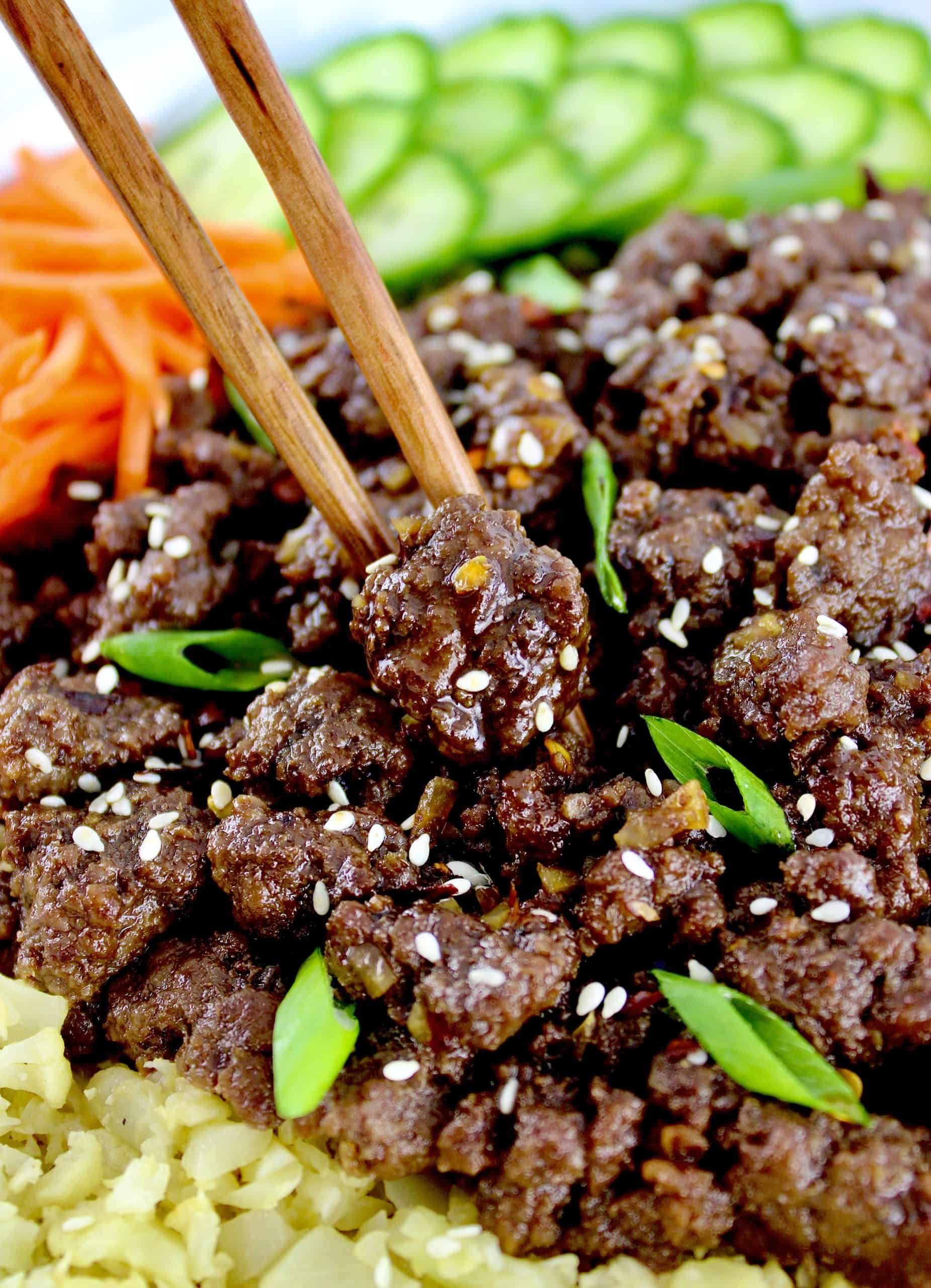 Korean Beef Bowl with chopsticks holding a piece of beef