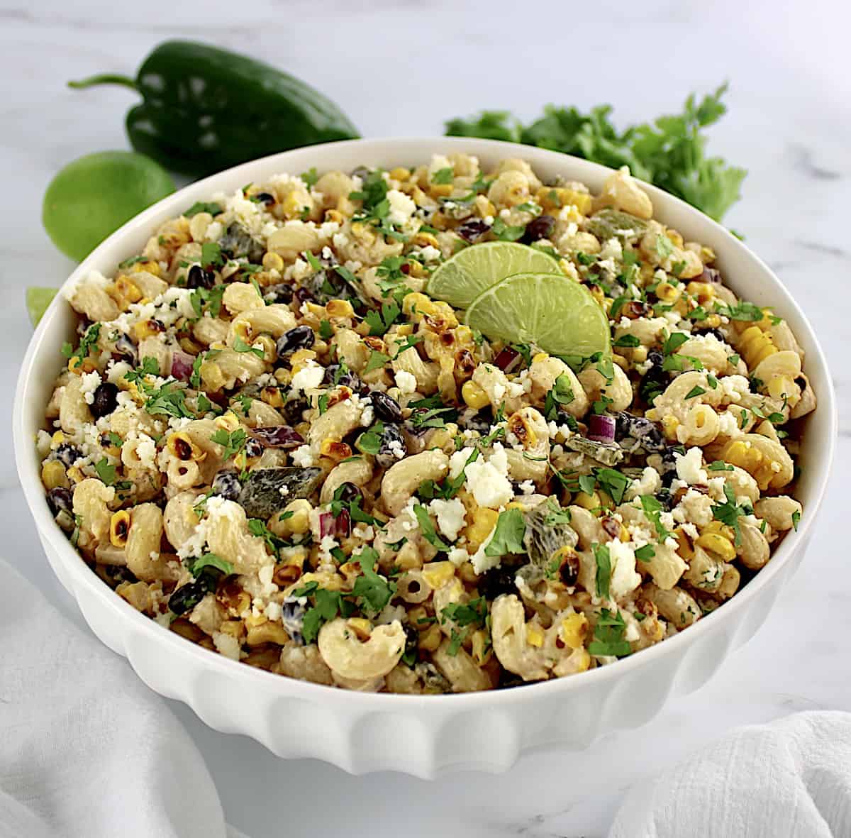 Mexican Street Corn Pasta Salad in white bowl with lime slices on top