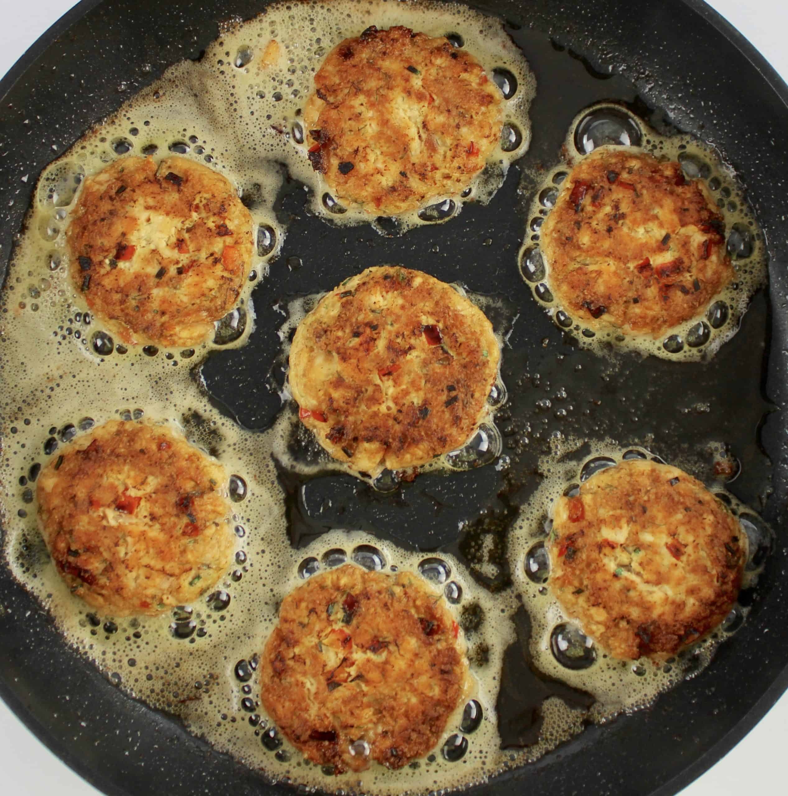7 salmon patties cooking in skillet