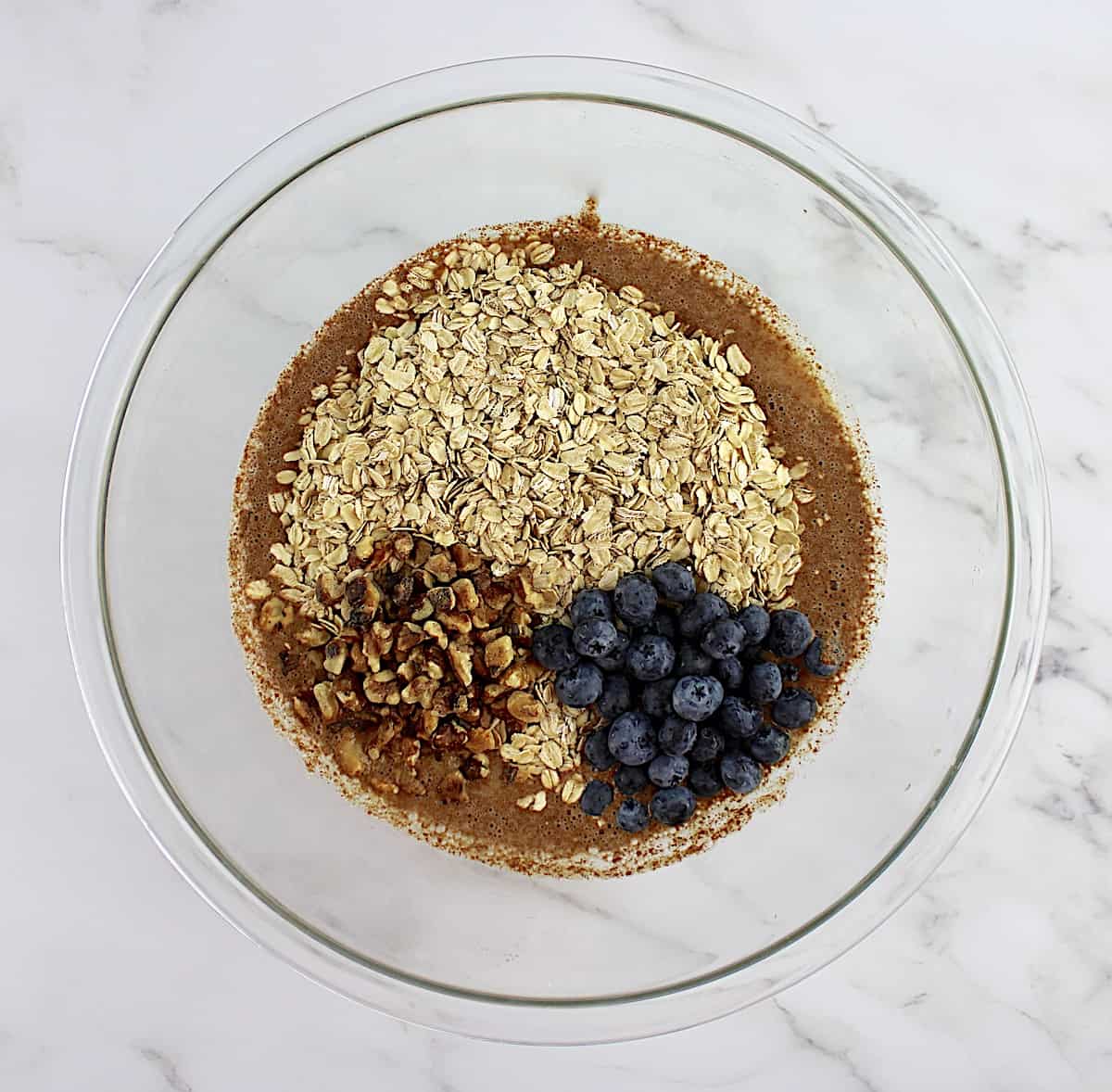 Vegan Baked Oats with blueberries and walnuts in glass bowl unmixed