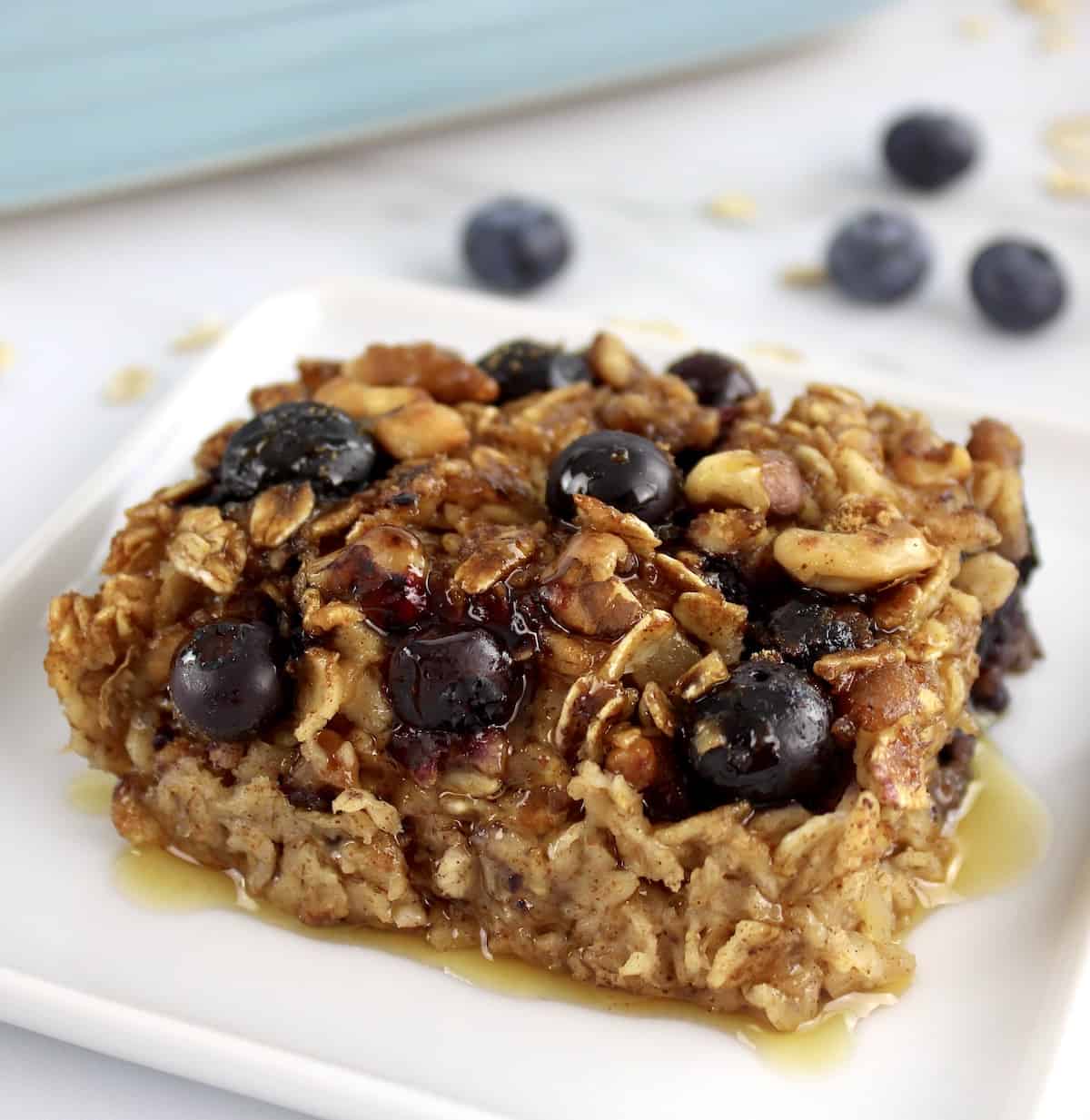 closeup of a slice of Vegan Baked Oats with blueberries on white plate
