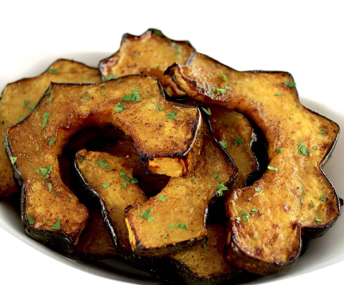 Air Fryer Acorn Squash slices on white plate with chopped parsley