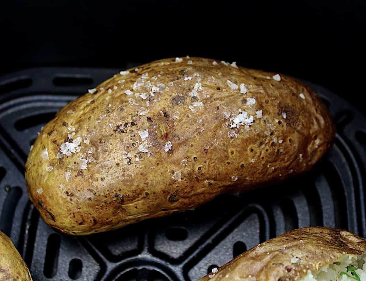closeup of air fryer baked potato in air fryer basket