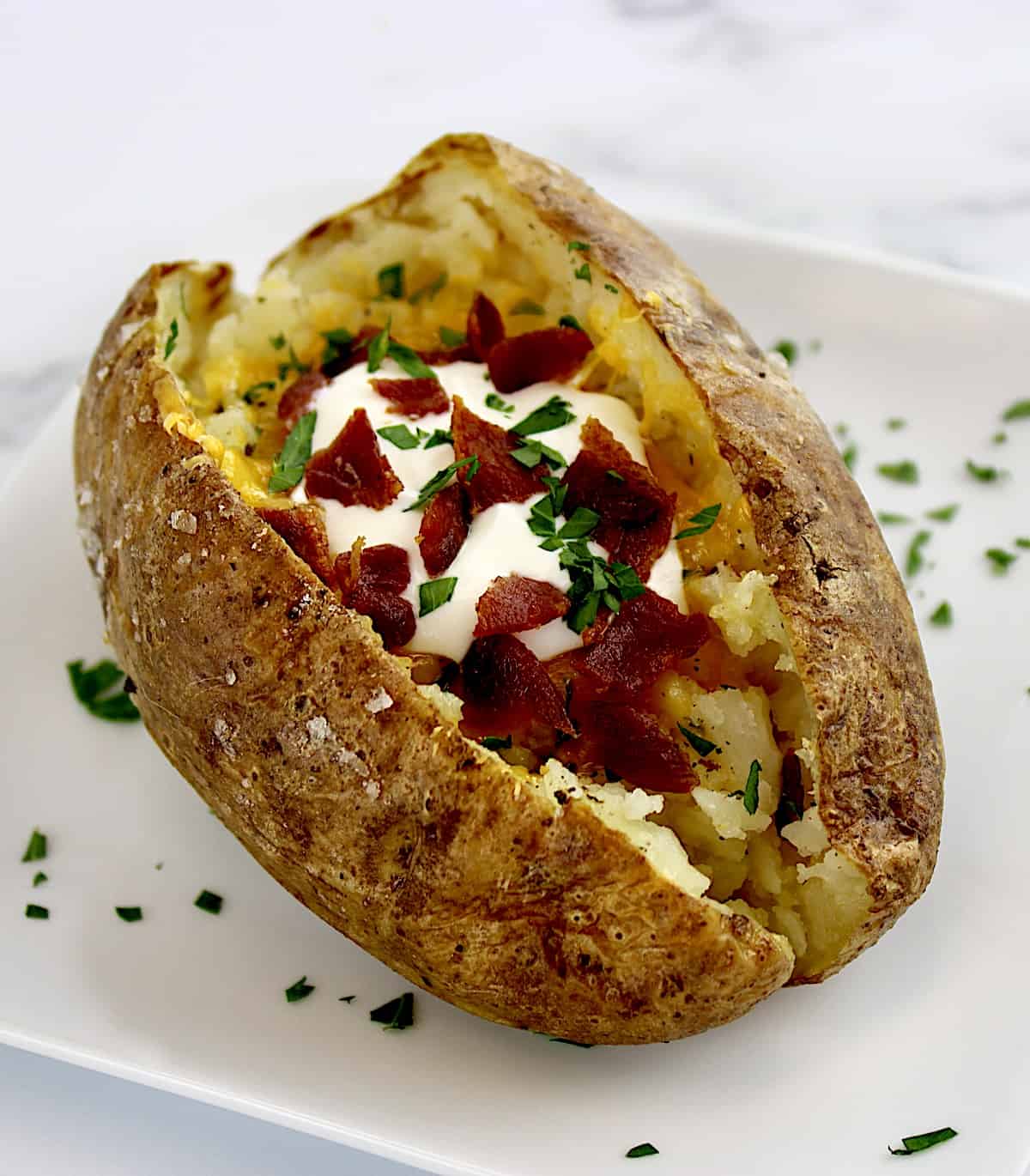 loaded baked potato on white square plate