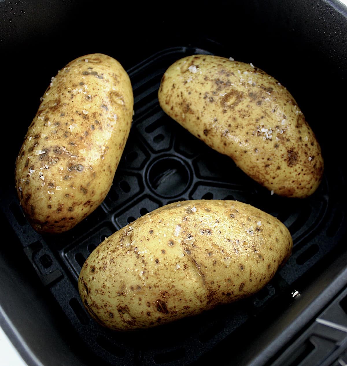 3 raw potatoes with olive oil and salt in air fryer basket