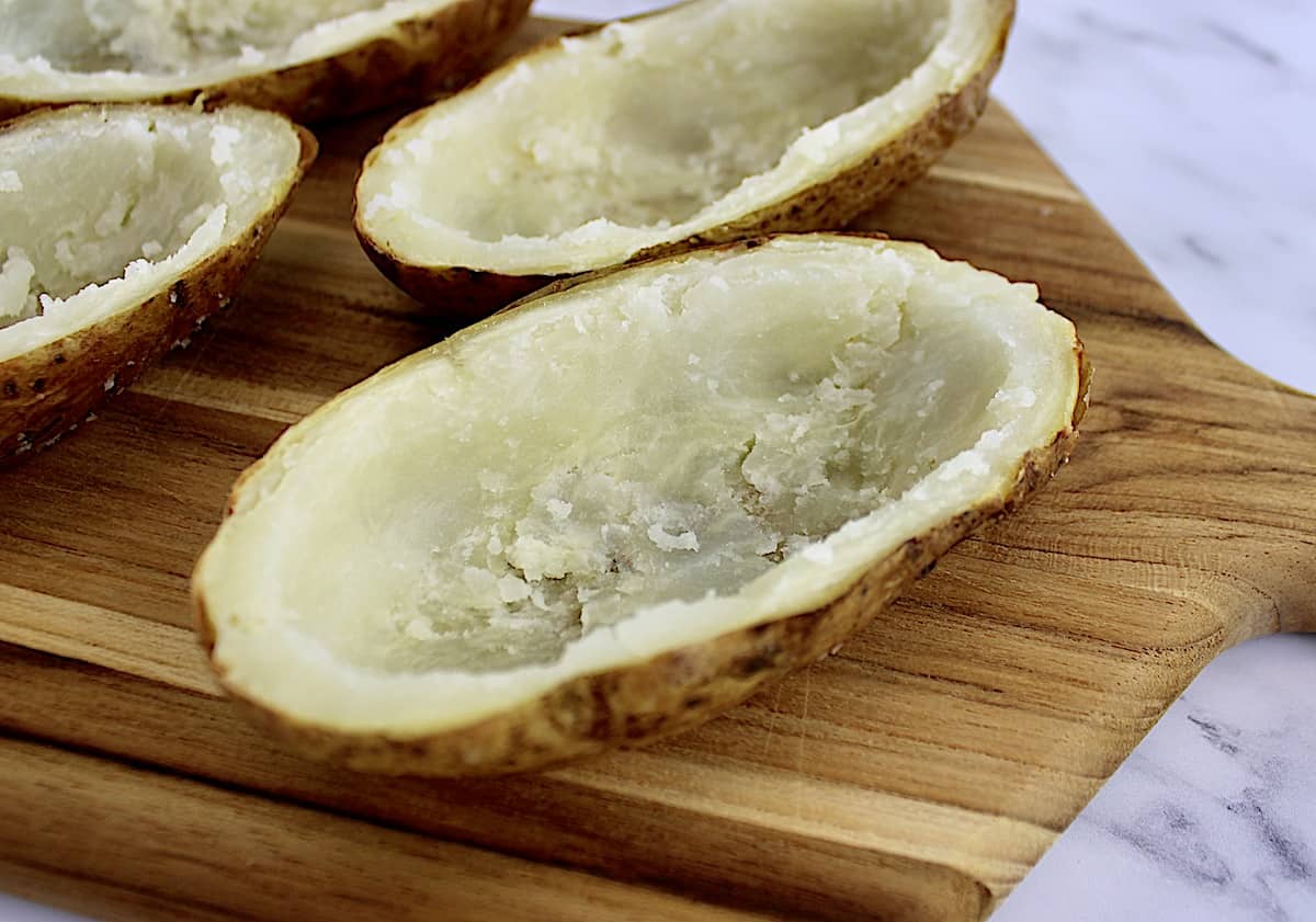 closeup of baked potato on cutting board with insides scooped out