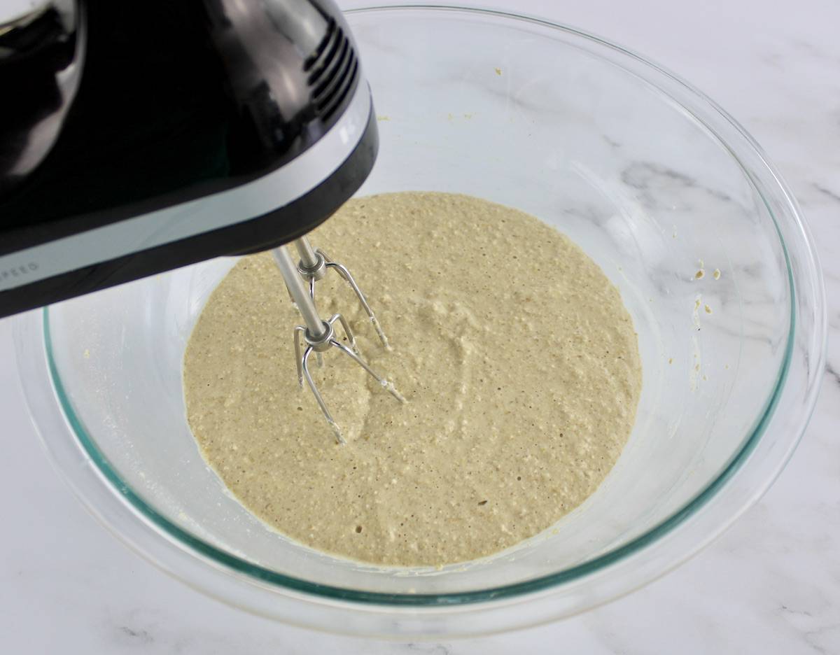 Banana Oat Flour Pancakes batter being mixed with hand mixer in glass bowl