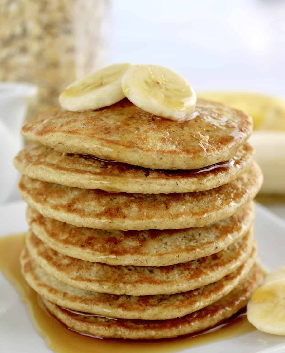 Banana Oat Flour Pancakes stack with sliced bananas over top