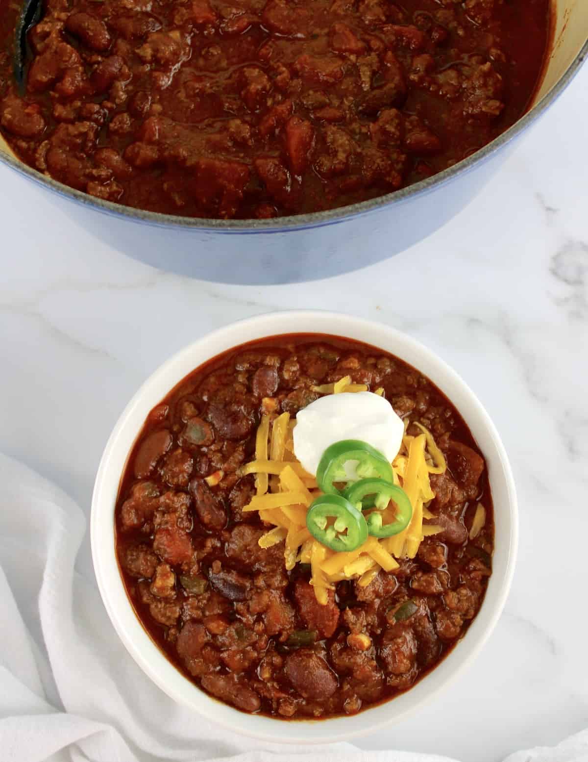 Best Homemade Chili in white bowl with blue pot in background
