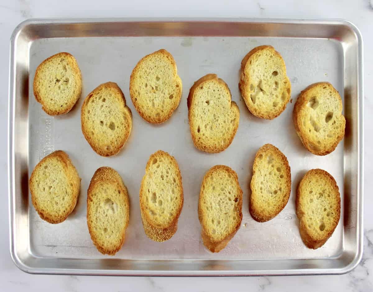12 slices of Italian bread with olive oil on baking sheet