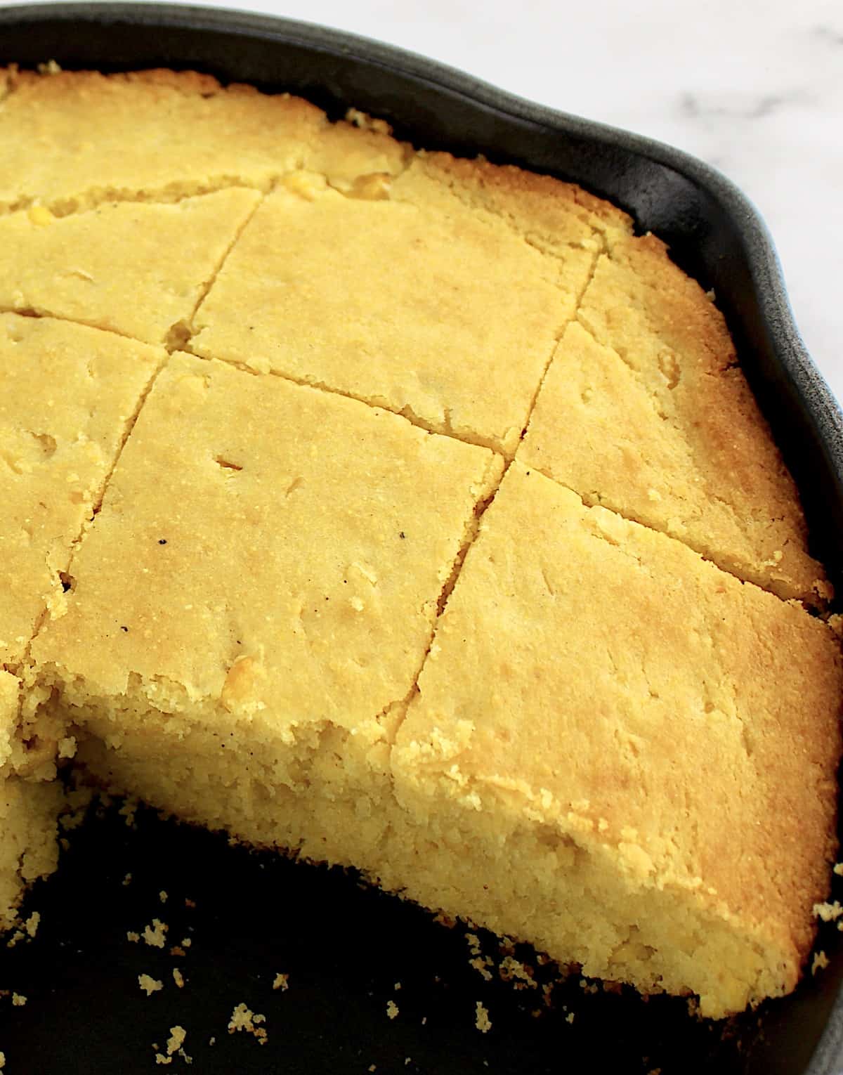 Gluten Free Cornbread in cast iron skillet cut into slices with some missing