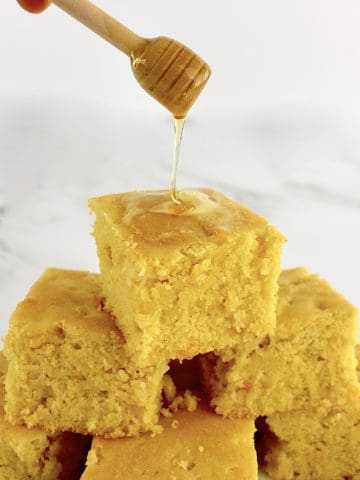 Gluten Free Cornbread slice with honey being drizzled over top